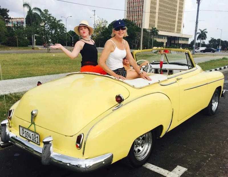 Travelers riding through Cuba in a vintage convertible
